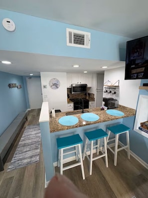 A compact kitchen with a central island, white cabinets, and a built-in microwave. - Oceanfront Escape w/ Balcony + 4 pools (Orange Beach)