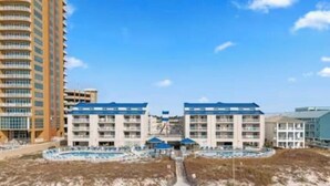 Un hotel sulla spiaggia con diversi edifici, una piscina e una zona di spiaggia sabbiosa.