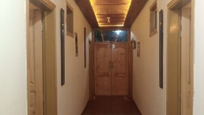 A hallway with wooden doors, a wooden ceiling, and a light fixture. - Hunza Nimbus hotel  (Karimabad)