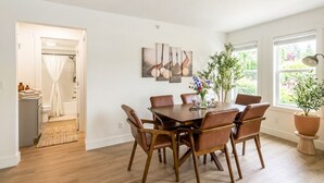 Un coin repas avec une table et des chaises en bois, un tableau accroché au mur et une plante en pot.