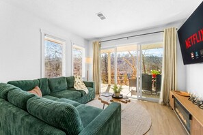 A living room with a green sofa, a coffee table, and a fireplace. - 2BR Creekside Branson Condo w/Bunk, Balcony, Pools, Gym & Resort Access~Sleeps 8 (Branson)