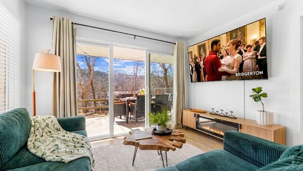 Un salon moderne avec un téléviseur, des canapés verts, une table basse et une cheminée.