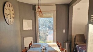 A dining area with a long table, chairs, a clock, and a view through a window. - Comfortable residence in Sarlat-la-Canéda (Sarlat-la-Canéda)