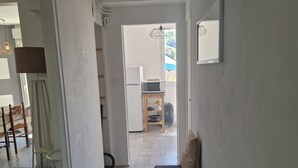A hallway with a sofa, a microwave, and a small table with a fan. - Comfortable residence in Sarlat-la-Canéda (Sarlat-la-Canéda)