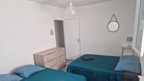 A bedroom with two beds, a dresser, a door, a mirror, and a lamp. - Comfortable residence in Sarlat-la-Canéda (Sarlat-la-Canéda)