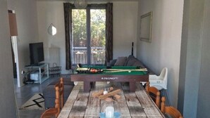 A dining area with a wooden table, chairs, a pool table, and a television in the background. - Comfortable residence in Sarlat-la-Canéda (Sarlat-la-Canéda)