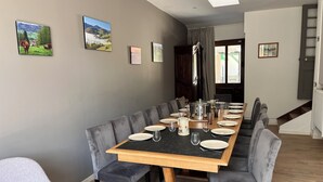 Un espace repas avec une longue table, des chaises à revêtement gris et un plateau en marbre noir.