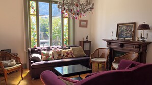 Un salon avec un canapé, des fauteuils, une cheminée et un lustre.