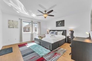 A bedroom with a bed, bedside tables, a desk, a ceiling fan, and a window with curtains. - Norval Cozy Rentals - Luxury - 5 Mins Mount Pleasant (Brampton)