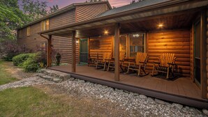 A log cabin with a porch, rocking chairs, and a stone pathway.
