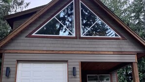 Une maison moderne dotée d’un garage, d’un porche abrité et d’une cheminée en pierre.