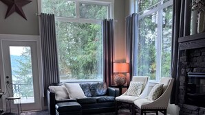 Un salon spacieux doté d’une grande fenêtre, d’une cheminée, d’un canapé en cuir et d’un tapis original en peau de vache.