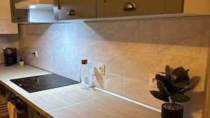 A kitchen with a wooden countertop, a built-in stove, cabinets, and a potted plant. - Le Parisien - cœur de st-brieuc (Saint-Brieuc)