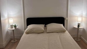A bed with two pillows, a black headboard, and two bedside tables with lamps. - Le Parisien - cœur de st-brieuc (Saint-Brieuc)