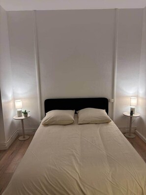 A bed with two pillows, a black headboard, and two bedside tables with lamps. - Le Parisien - cœur de st-brieuc (Saint-Brieuc)