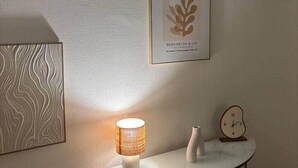 A wall with framed artwork, a lamp, and a clock on a small table. - Le Parisien - cœur de st-brieuc (Saint-Brieuc)