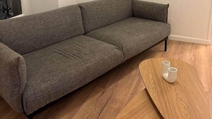 A gray sofa, a wooden coffee table with two white cups, and a framed picture on the wall. - Le Parisien - cœur de st-brieuc (Saint-Brieuc)