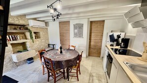 A compact kitchen with a dining table, chairs, a built-in oven, and a coffee maker. - The Pechplazen grangette (Rudelle)