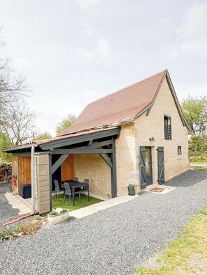 A single-story house with a sloped roof, a covered patio, and a gravel driveway.
