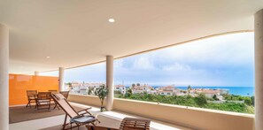 Ein Balkon mit Meerblick, einem Tisch mit Stühlen und einem Blumentopf.