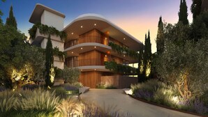Un hotel de varios pisos con balcones, techo curvo y jardines ajardinados alrededor.