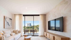 Een moderne woonkamer met een bank, een salontafel, een televisie en een balkon met uitzicht over de stad.
