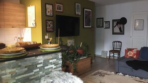 A living room with a stone fireplace, a flat-screen TV mounted on the wall, and a sofa with a throw blanket. - LOVELY LITTLE NEST FOR UP TO 5 PEOPLE, PETS WELCOME (Nice)