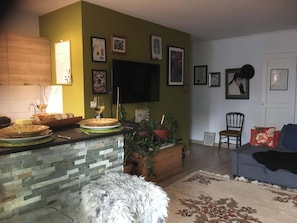 Ein Wohnzimmer mit Kamin aus Stein, einem an der Wand befestigten Flachbildfernseher und einem Sofa mit einer Decke.