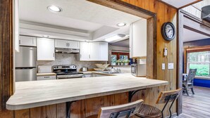 Una cucina con isola centrale, elettrodomestici in acciaio inossidabile e rivestimenti in legno.