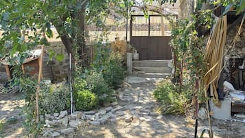 Un camí al jardí que condueix a un edifici amb mur de pedra i estructura de fusta.