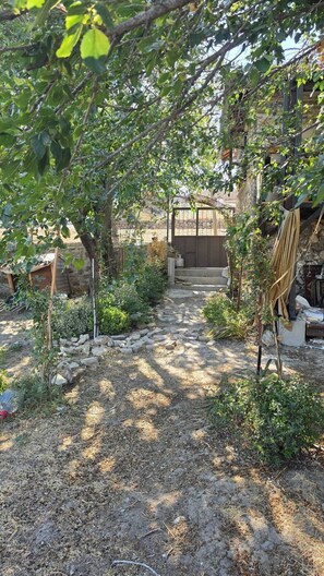 Un sendero en un jardín que lleva a un edificio con un muro de piedra y una estructura de madera.