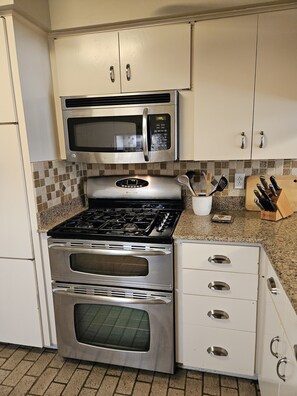 A kitchen with stainless steel appliances, including a microwave and oven, and a granite countertop.