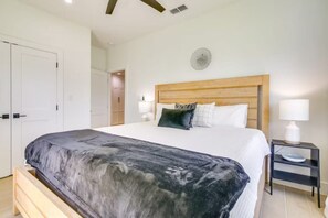 A bedroom with a bed, bedside tables, a wooden headboard, and a door.