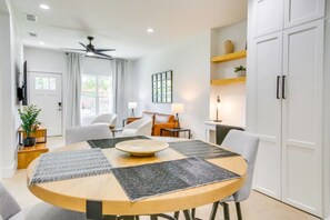 A modern dining area with a round table, chairs, a ceiling fan, and a view of the outdoors.