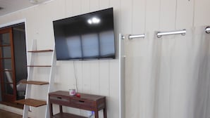 A room with a TV mounted on the wall, a wooden console table, a white curtain, and a wooden ladder. - Beautiful 2 Bed/2 Bath Cozy Cottage Retreat — Your Home Away From Home (Sarasota)
