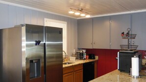 A kitchen with a stainless steel refrigerator, wooden cabinets, a granite countertop, and a built-in oven. - Beautiful 2 Bed/2 Bath Cozy Cottage Retreat — Your Home Away From Home (Sarasota)