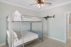 A bunk bed room with a ceiling fan, a shark decoration, and a hallway. - Beachfront + Private Hot Tub, Pet Friendly, Hammock + Swings, Loaded, Sleeps 12 (Dauphin Island)