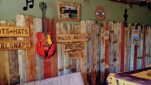 Ein Zimmer mit einer rustikalen Holzwand, einer roten Gitarre, einer Couch und einem farbenfrohen Teppich.