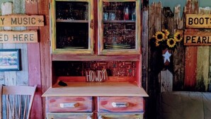 Ein rustikaler Raum mit einer Vintage-Jukebox mit der Aufschrift 'Boot Scootin' Boogie und einem Schild mit der Aufschrift 'Howdy'.