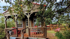 Eine Holzhütte mit Veranda, einem Schild mit der Aufschrift 'Wipe Your Buckin Boots' und einer rustikalen Außenanlage.