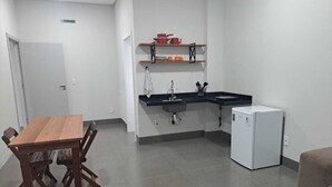 A compact kitchen with a dining table, a refrigerator, and a built-in sink. - LU'S HOUSE APARTMENTS (102) (Primavera do Leste)