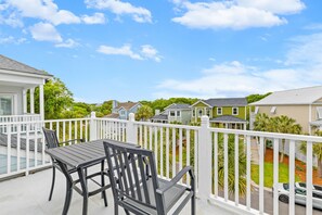 Ein Balkon mit Tisch und Stühlen, weißen Geländern und Häusern im Hintergrund.