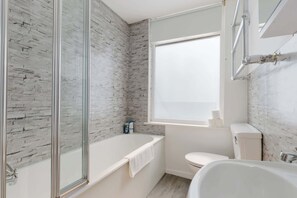 Ein Badezimmer mit Badewanne, Toilette und einem Fenster.
