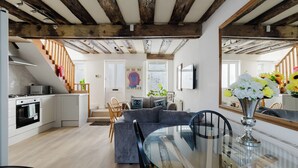A modern kitchen with a microwave, stove, and cabinets. There is a dining area with a glass table and chairs. A sofa and a chair are placed in the living room. - The Beatles Inspired 3BDR Home by Abbey Road (Greater London)