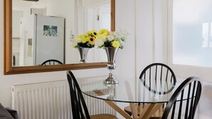A dining area with a glass table, black chairs, a flower vase, and a large mirror on the wall. - The Beatles Inspired 3BDR Home by Abbey Road (Greater London)