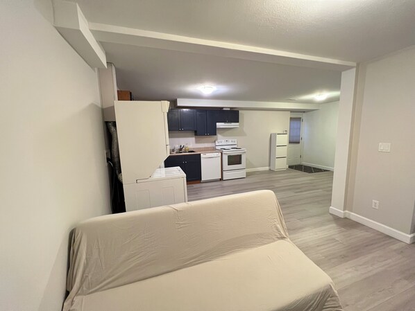 Um apartamento moderno com cozinha compacta, área de refeições e sala de estar com sofá.