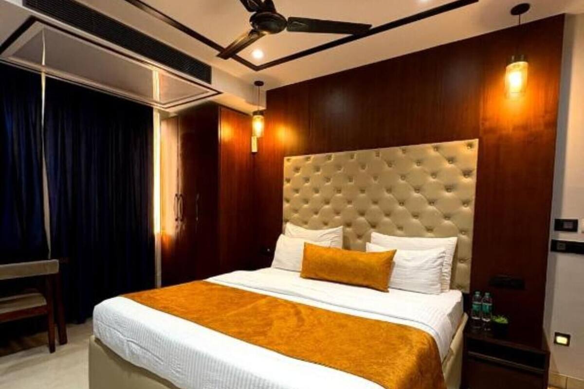 A modern hotel room with a large bed, a ceiling fan, and a nightstand with a lamp.