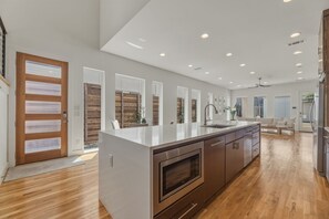 Una cuina moderna amb una illa gran, terra de fusta i vista a la zona de sala d'estar.