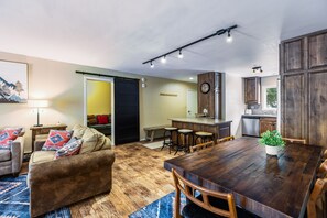 A modern living space with a dining area, kitchen, and a large window. - Lake Fork - Ski-In / Ski-Out, Gas Stove, Parking (Taos Ski Valley)