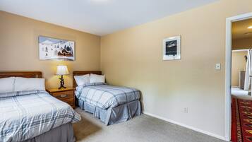 A hotel room with two beds, a nightstand with a lamp, and two framed pictures on the wall.